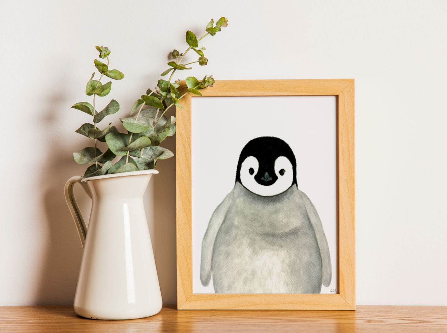 Framed penguin nursery art print next to vase with greenery